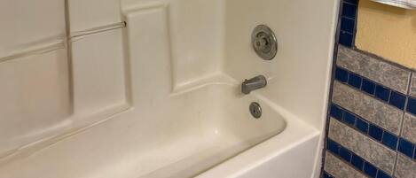 A bathtub with a showerhead, a towel rack, and a tiled wall.