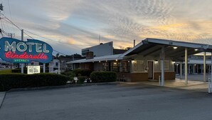 Un motel llamado 'Cinderella' con un cartel de 'VACANCY', un área de estacionamiento techada y un edificio con fachada de ladrillo.