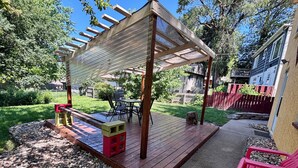 Un patio techado con terraza de madera, una mesita y una silla.