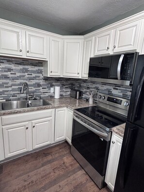 Enjoy cooking in this well-equipped kitchen with a stainless steel sink, microwave, oven, and refrigerator.
