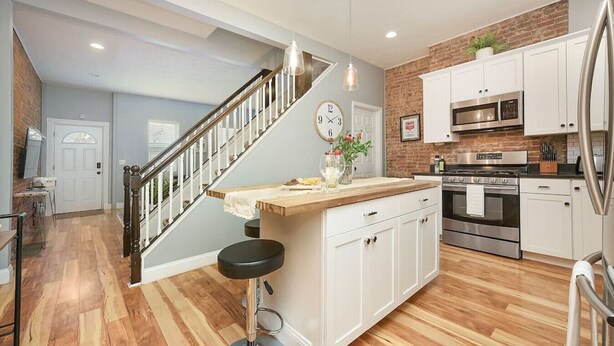 A modern kitchen with white cabinets, a stainless steel refrigerator, and a wooden island.