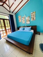 Un dormitorio con una cama grande, cabecera de madera y vistas a la vegetación a través de una ventana.