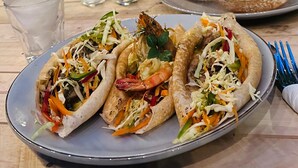 A dining table with a plate of tacos, a drink, and a basket of bread. - SURF N SPICE (Dikwella)