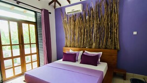 A bedroom with a bed, wooden headboard, and a view of the outdoors through a sliding door. - SURF N SPICE (Dikwella)