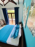 Un dormitorio con una cama grande, cortinas azules y una ventana con vistas a zonas verdes.