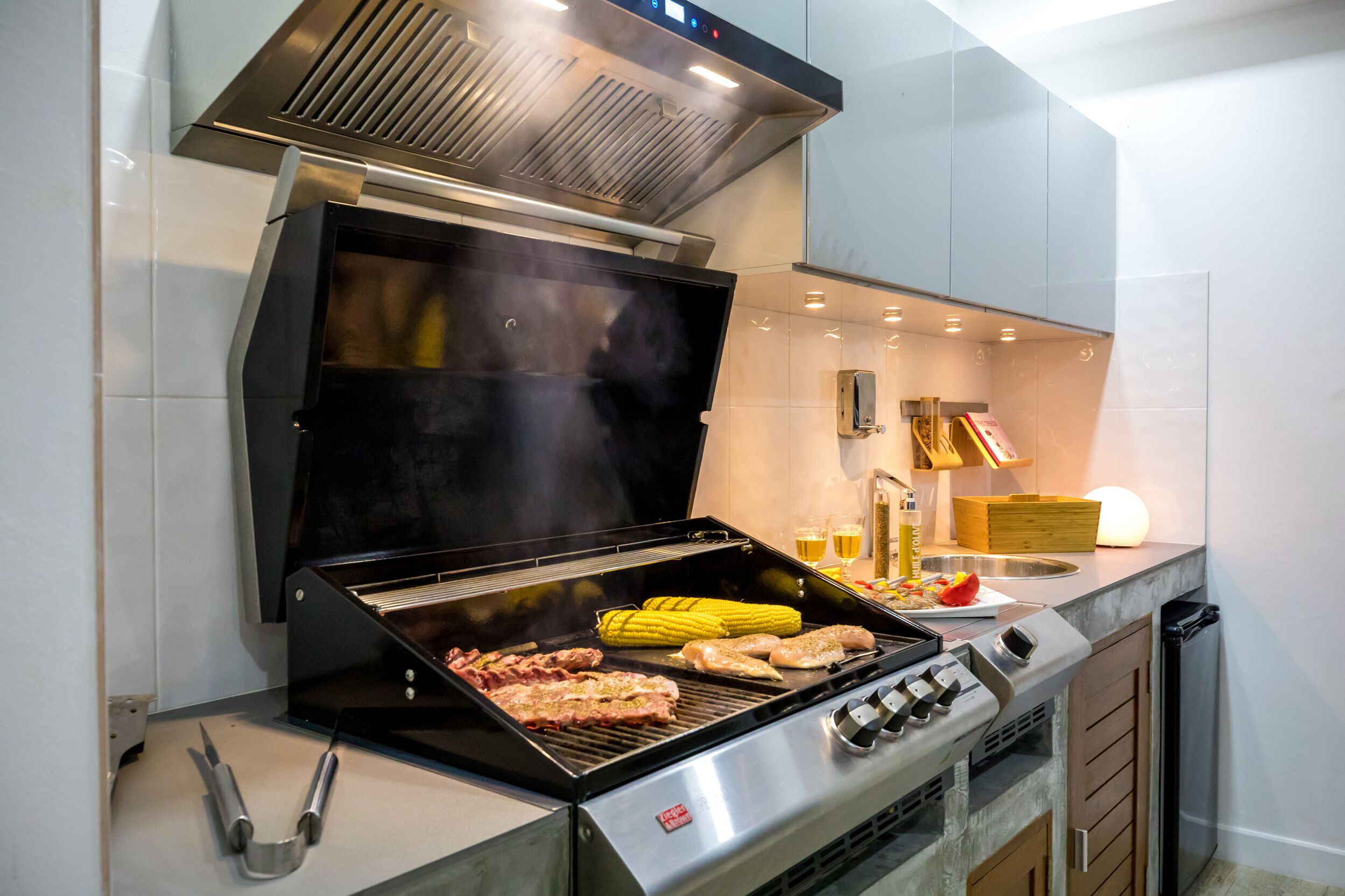 Una cocina moderna con una parrilla empotrada, electrodomésticos de acero inoxidable y un diseño limpio y minimalista.