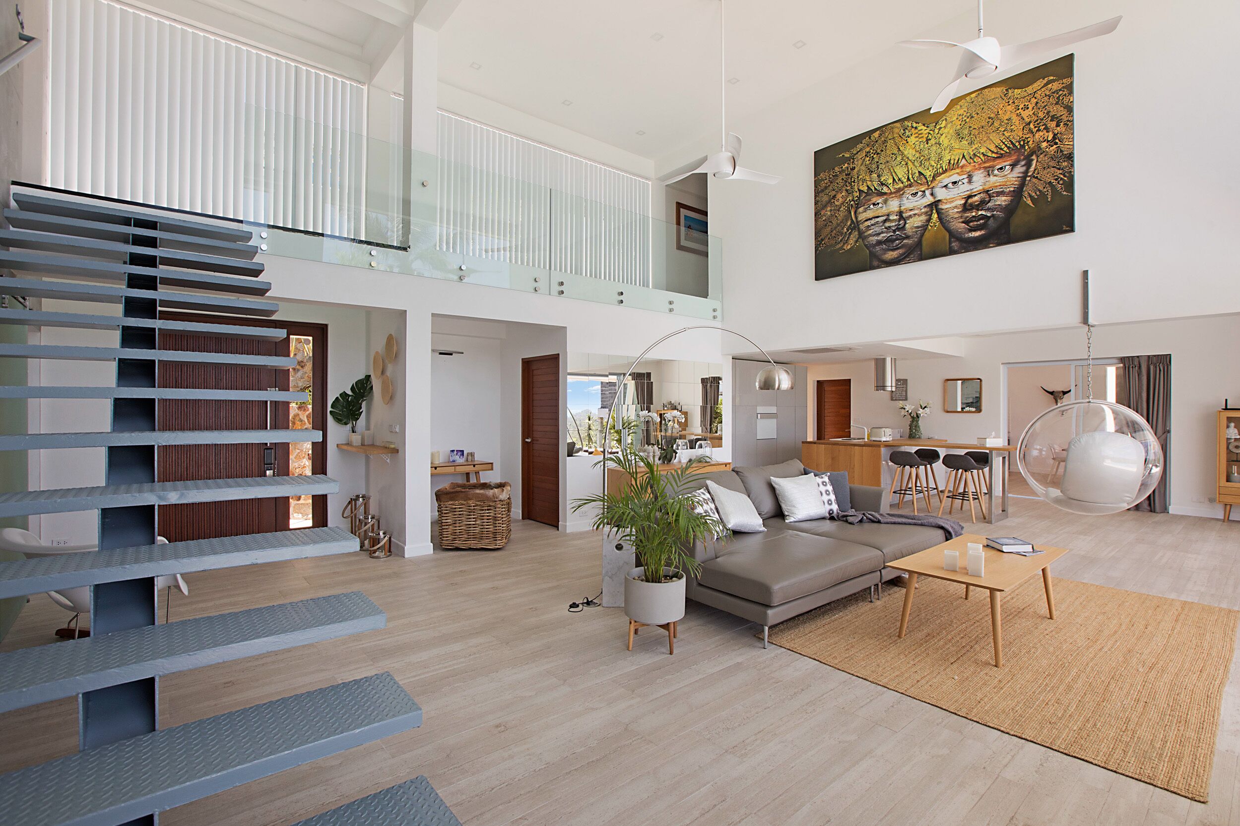 Een ruime woonkamer met een moderne trap, een eethoek en een keuken.