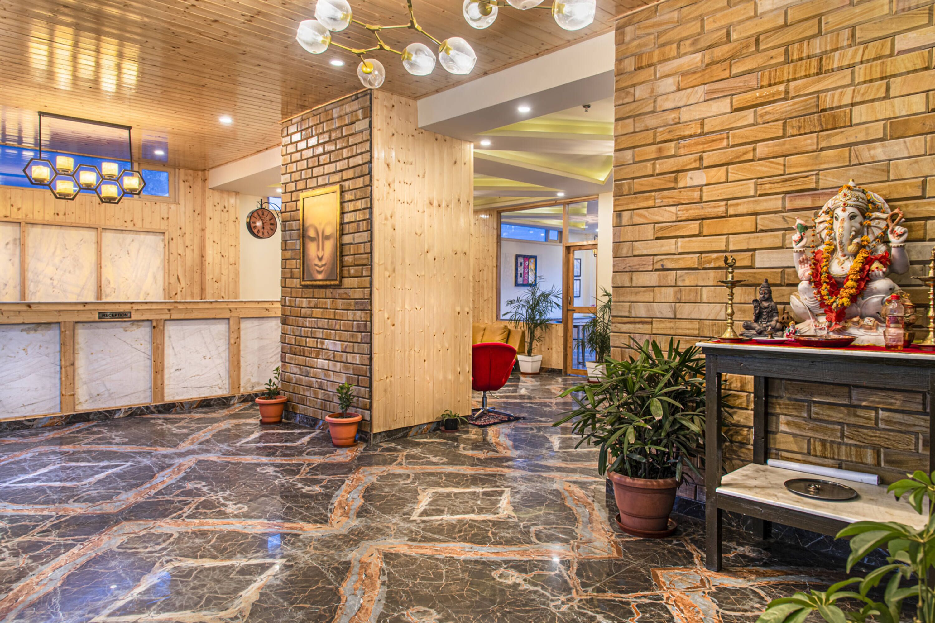 A lobby with a wooden reception desk, a clock, and a statue of a deity.