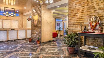 A lobby with a wooden reception desk, a clock, and a statue of a deity.