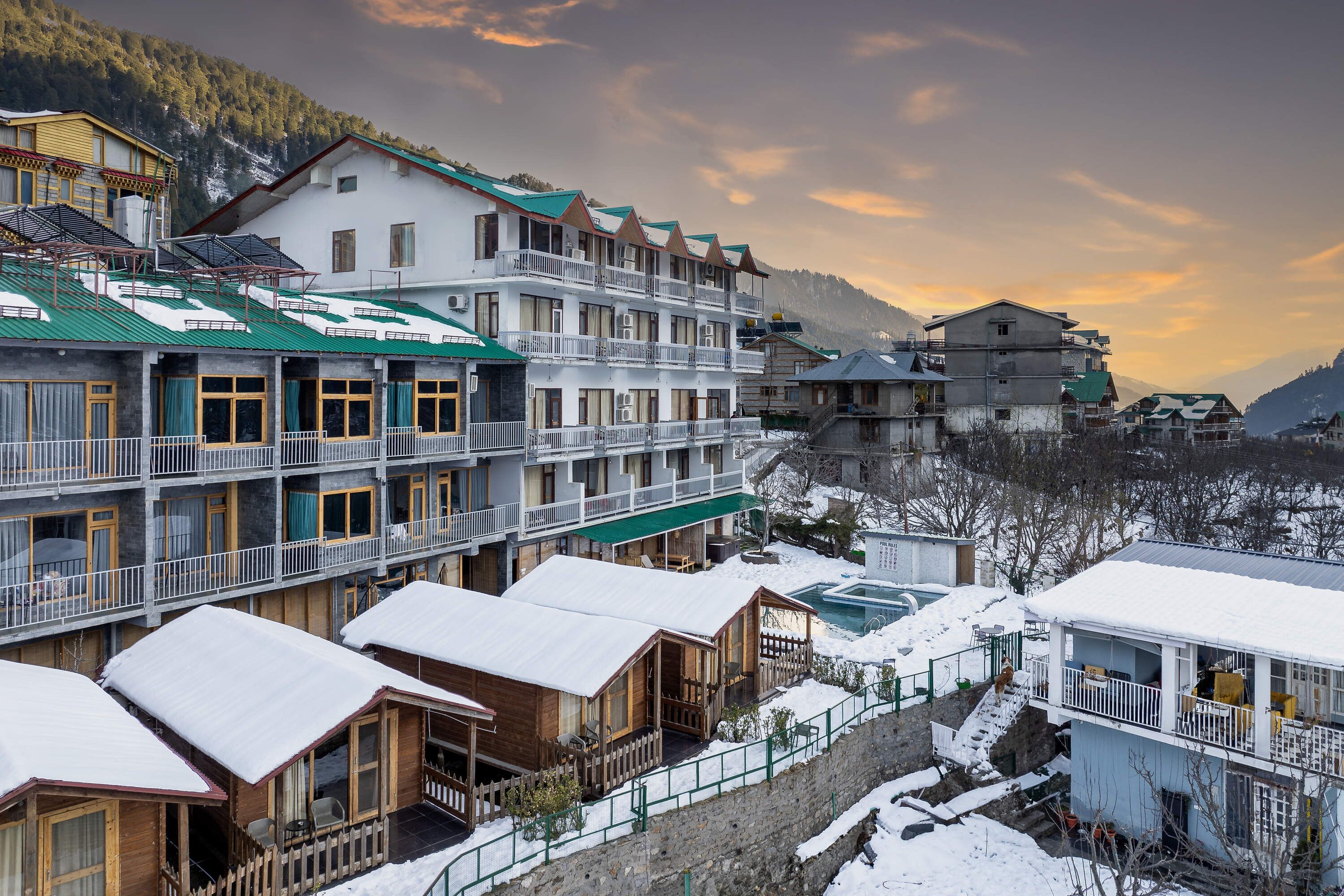 Un hôtel à plusieurs étages, doté de balcons, d’une piscine et offrant une vue sur les montagnes.