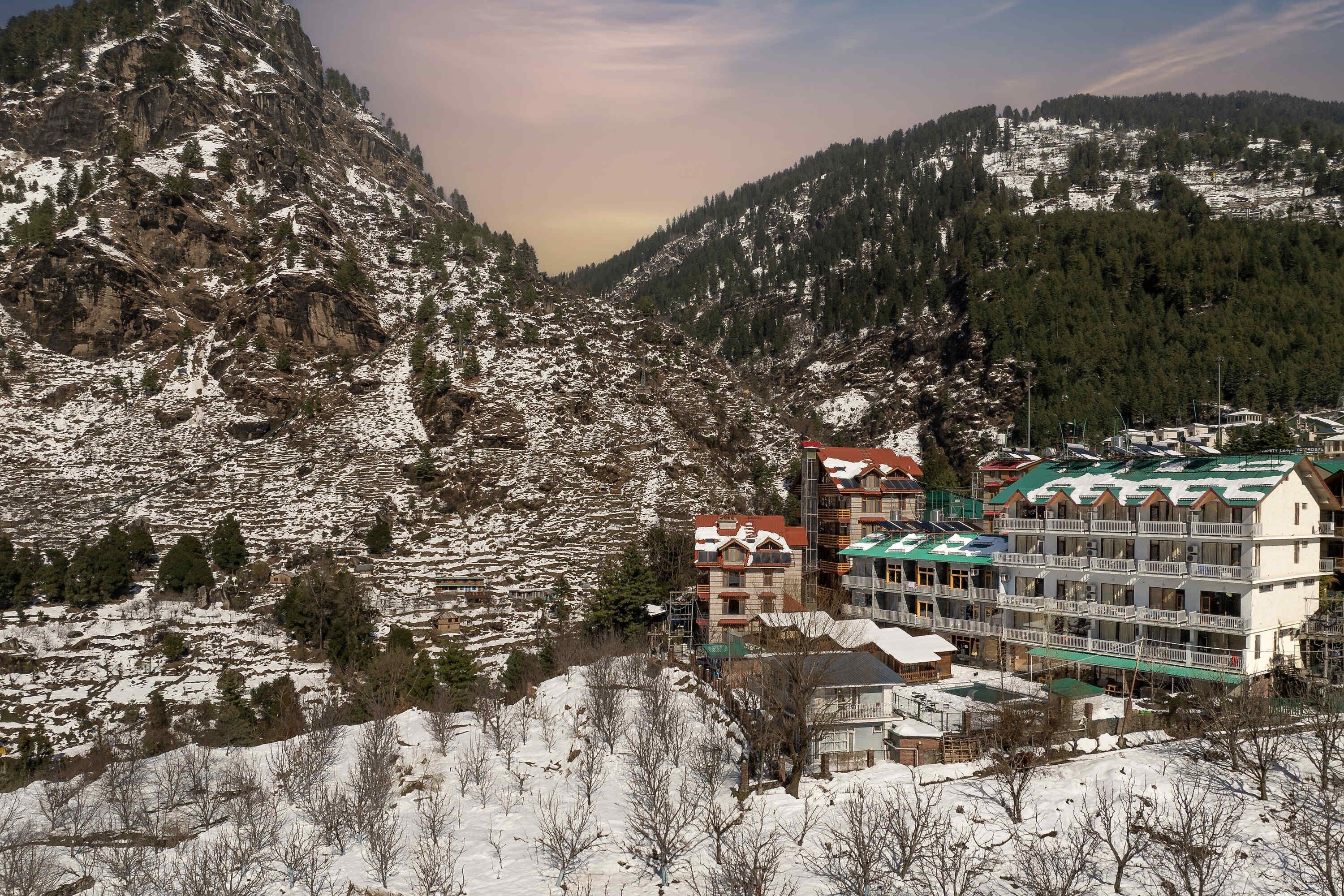 A mountainous area with snow-covered terrain and a multi-story building with balconies.