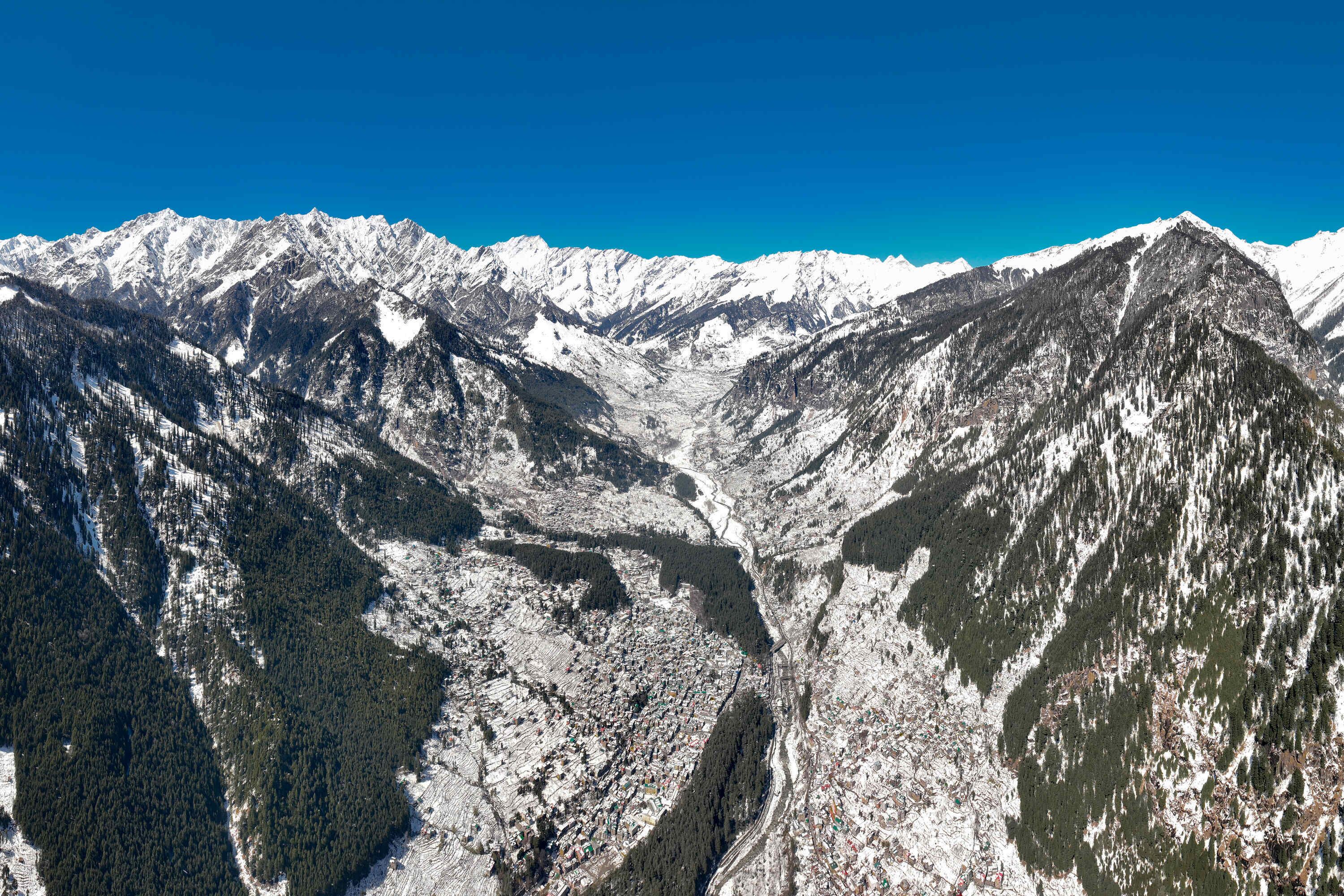 Un paisaje montañoso con picos nevados y un valle.