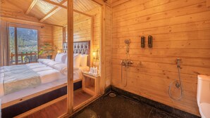 A wooden cabin room with a bed, a small bedside table, a shower area, and a view of the outdoors. - Echor Himalayan Heights Luxe Resort & Spa, Manali (Manali)