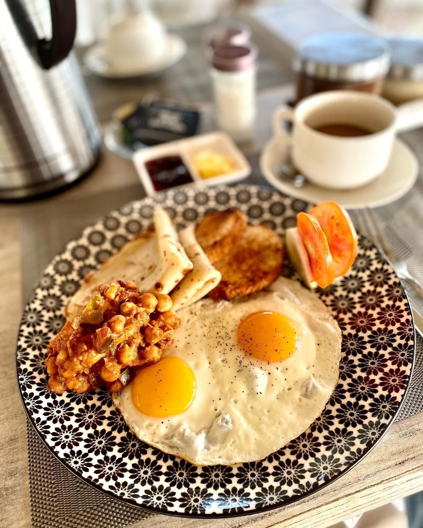 A plate with eggs, toast, and a side of fried food, served on a patterned plate.