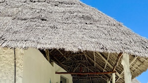 Une construction à toit de chaume, avec des marches menant à un point de vue sur la plage.