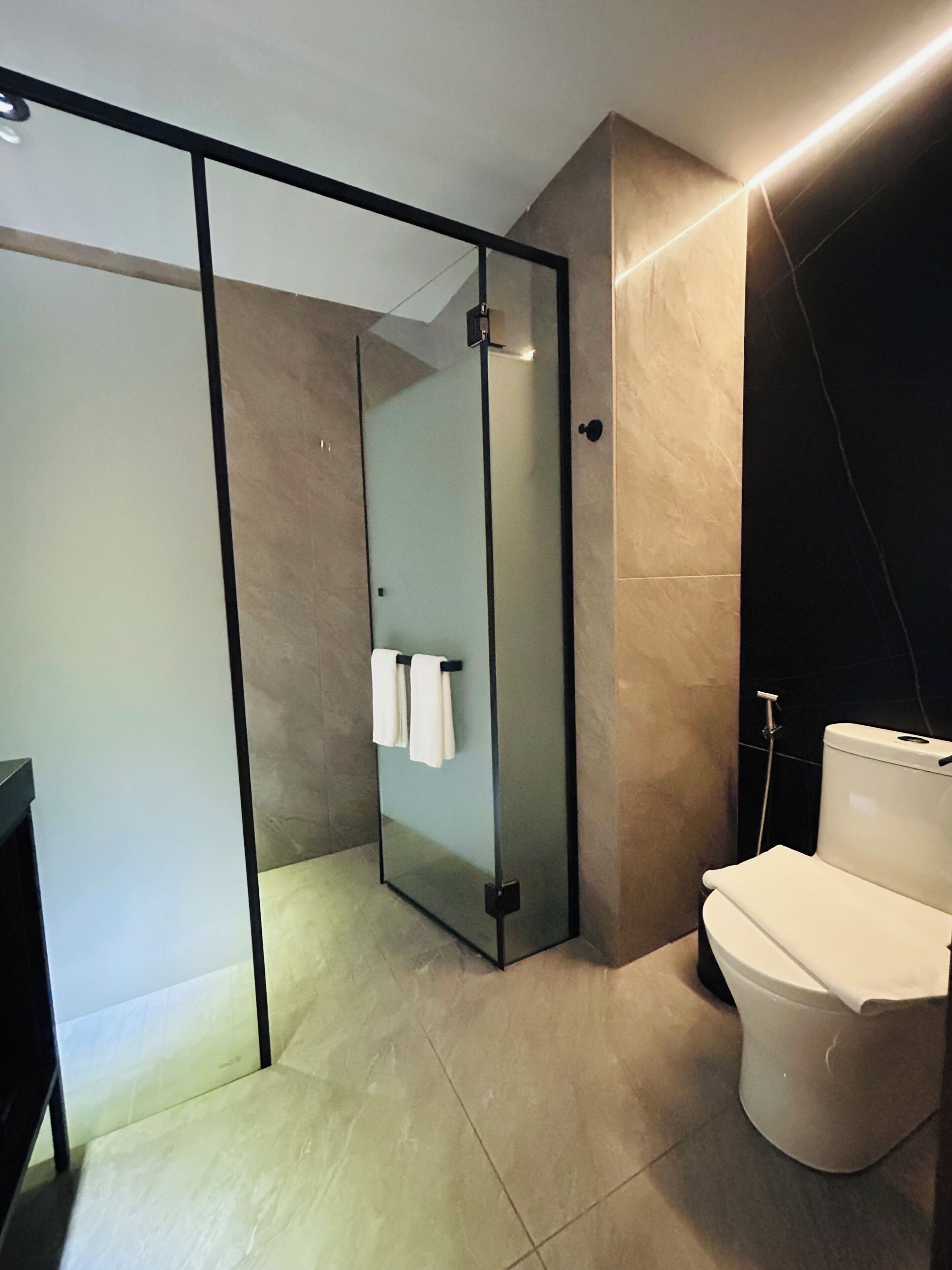 Ein modernes Badezimmer mit Duschkabine aus Glas, Toilette und Waschbecken.