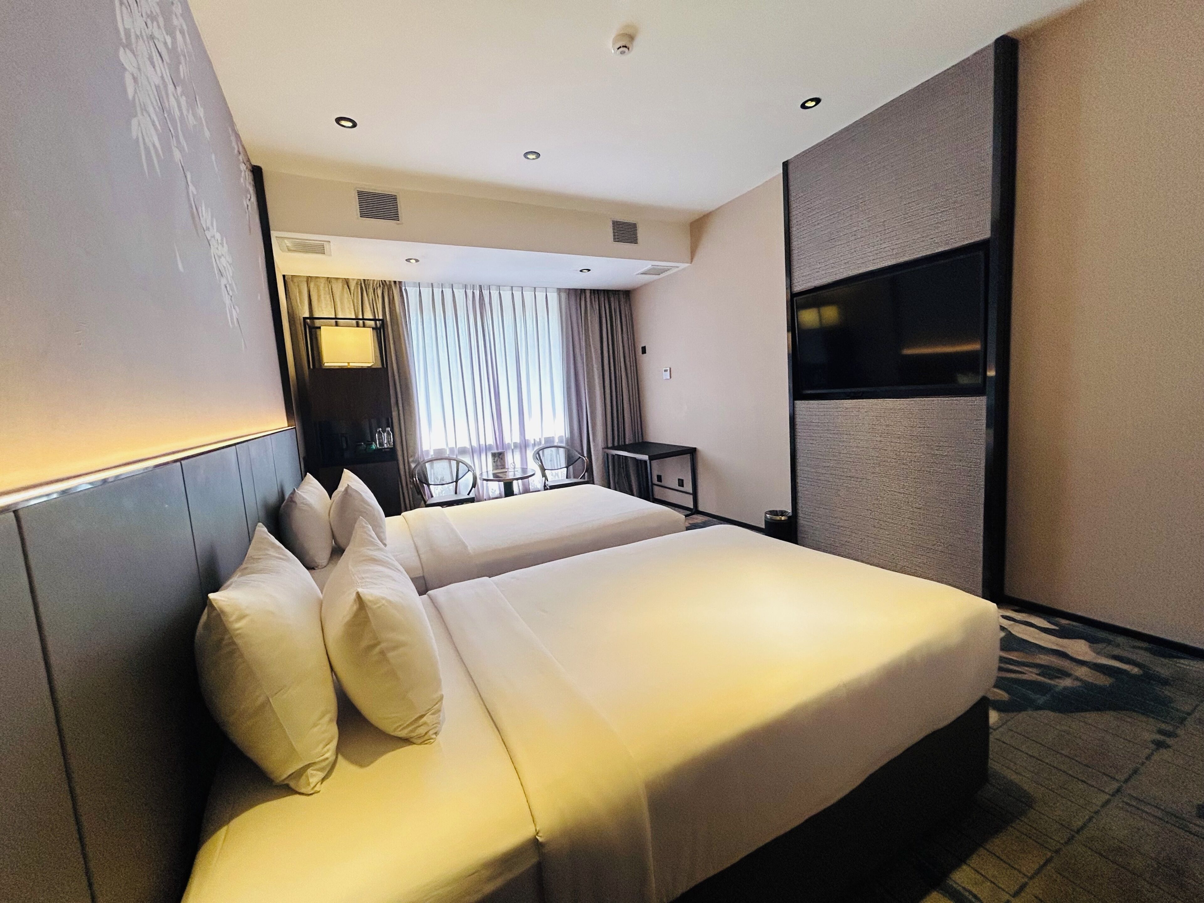 Una camera d'albergo con un letto grande, un tavolino e una televisione.