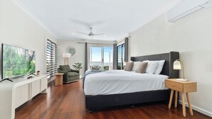 A modern bedroom with a large bed, a desk, a chair, and a view of the outdoors. - Seaside Rest at Clifton Beach (Clifton Beach)