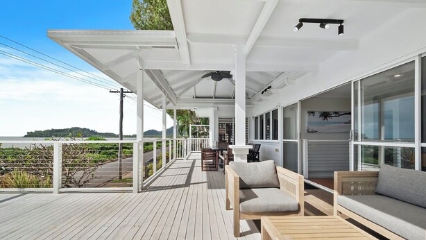 A covered outdoor deck with wooden furniture, a table, and chairs. - Seaside Rest at Clifton Beach (Clifton Beach)