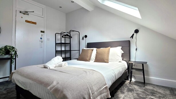 A bedroom with a bed, bedside table, lamp, and a skylight. - Claude Road Apartments by Switchback Stays (Cardiff)