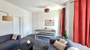 A living room with two sofas, a coffee table, a dining table, and a hanging light fixture. - Claude Road Apartments by Switchback Stays (Cardiff)