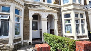 A historic building with multiple bay windows, a central entrance with an archway, and a brick pathway leading to the door. - Claude Road Apartments by Switchback Stays (Cardiff)