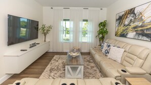Ein modernes Wohnzimmer mit einem Flachbildfernseher, einer Couch, einem Couchtisch und einem großen Gemälde.