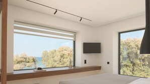 Un dormitorio moderno con un ventanal grande, un televisor de pantalla plana y una mesita de noche con un libro.