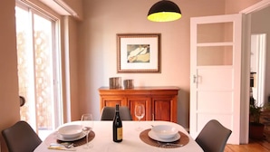 A dining area with a table set for two, a wine bottle, and a framed picture on the wall. - Private Terrace with Sun 15 minutes from Lisbon and the Airport (Odivelas)