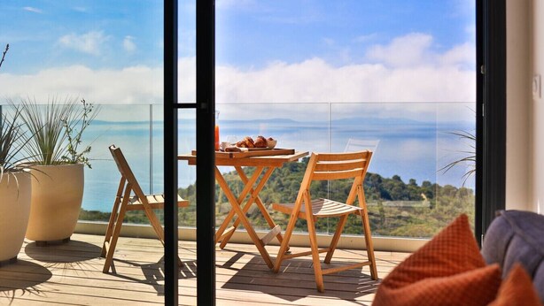 A balcony with a table and chairs, a potted plant, and a view of the sea. - 2-room apartment with panoramic sea view (Rayol-Canadel-sur-Mer)