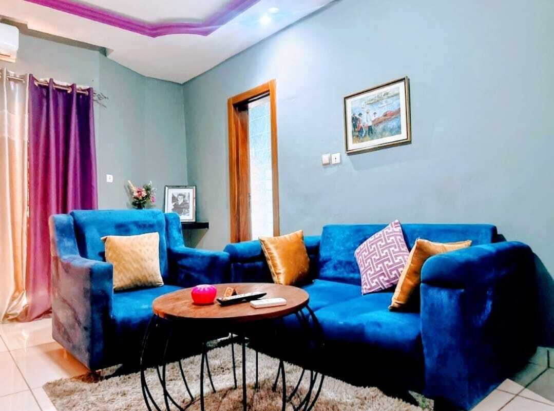 Un salon avec un canapé bleu, une table basse ronde et un tableau accroché au mur.