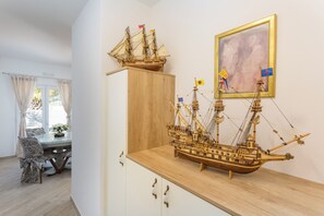 Un modelo de barco sobre una repisa de madera, una mesa de comedor con sillas y un cuadro en la pared.