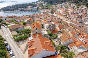 Un pueblo costero con edificios de tejas anaranjadas, un puerto deportivo y una calle con coches aparcados.