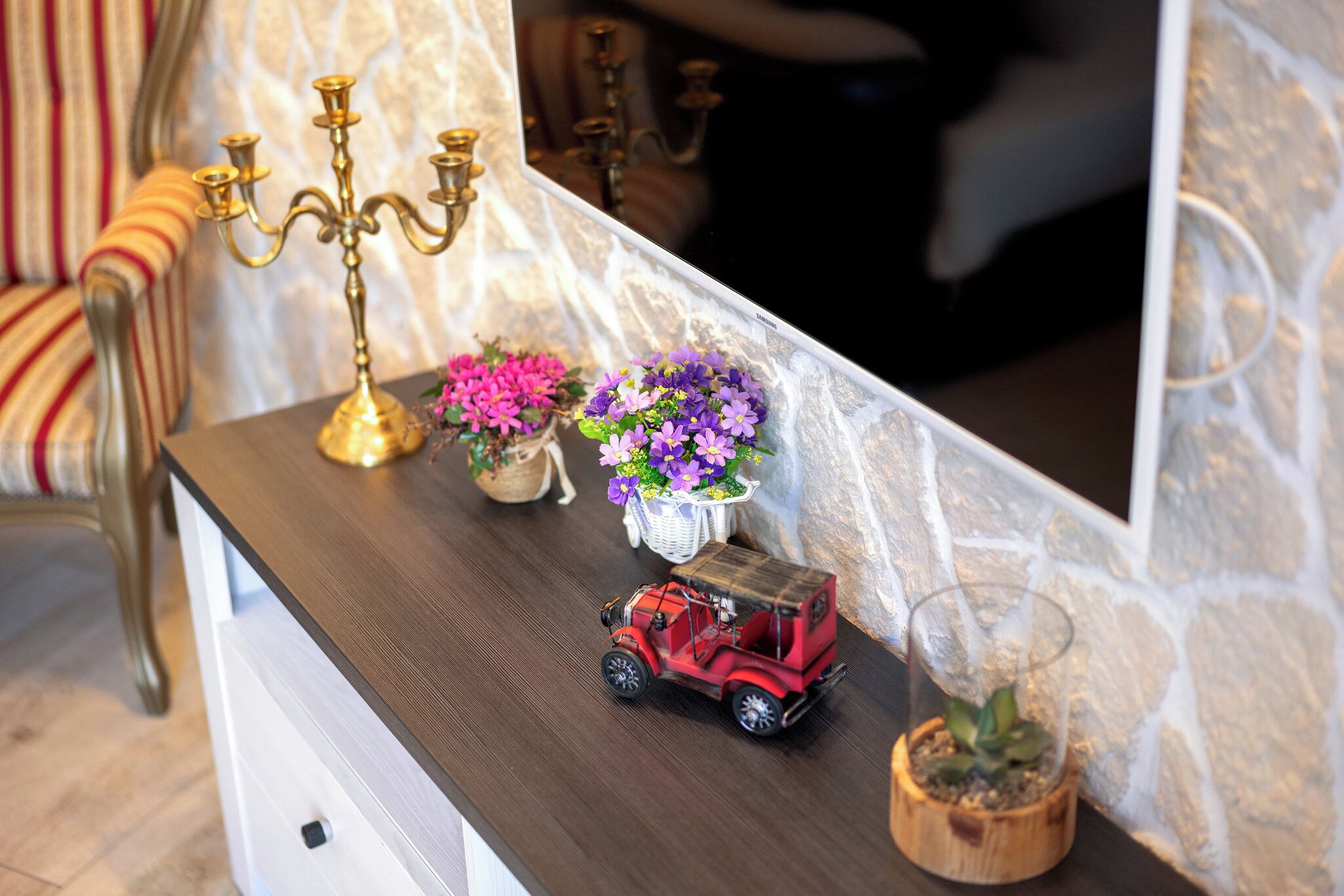 A wooden table with a red toy car, a gold candelabra, and two flower baskets.