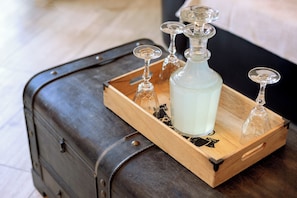 Una maleta de madera oscura con una botella de vidrio y copas de vino encima.
