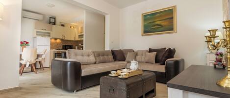 A modern living room with a sofa, a coffee table, and a dining area visible in the background.