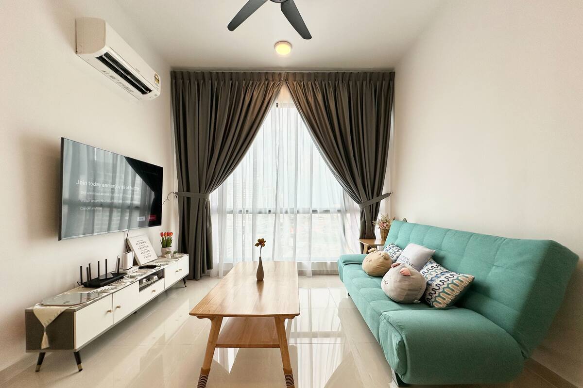 Un salon moderne avec un canapé de couleur turquoise, une table basse en bois, un téléviseur à écran plat et un ventilateur de plafond.
