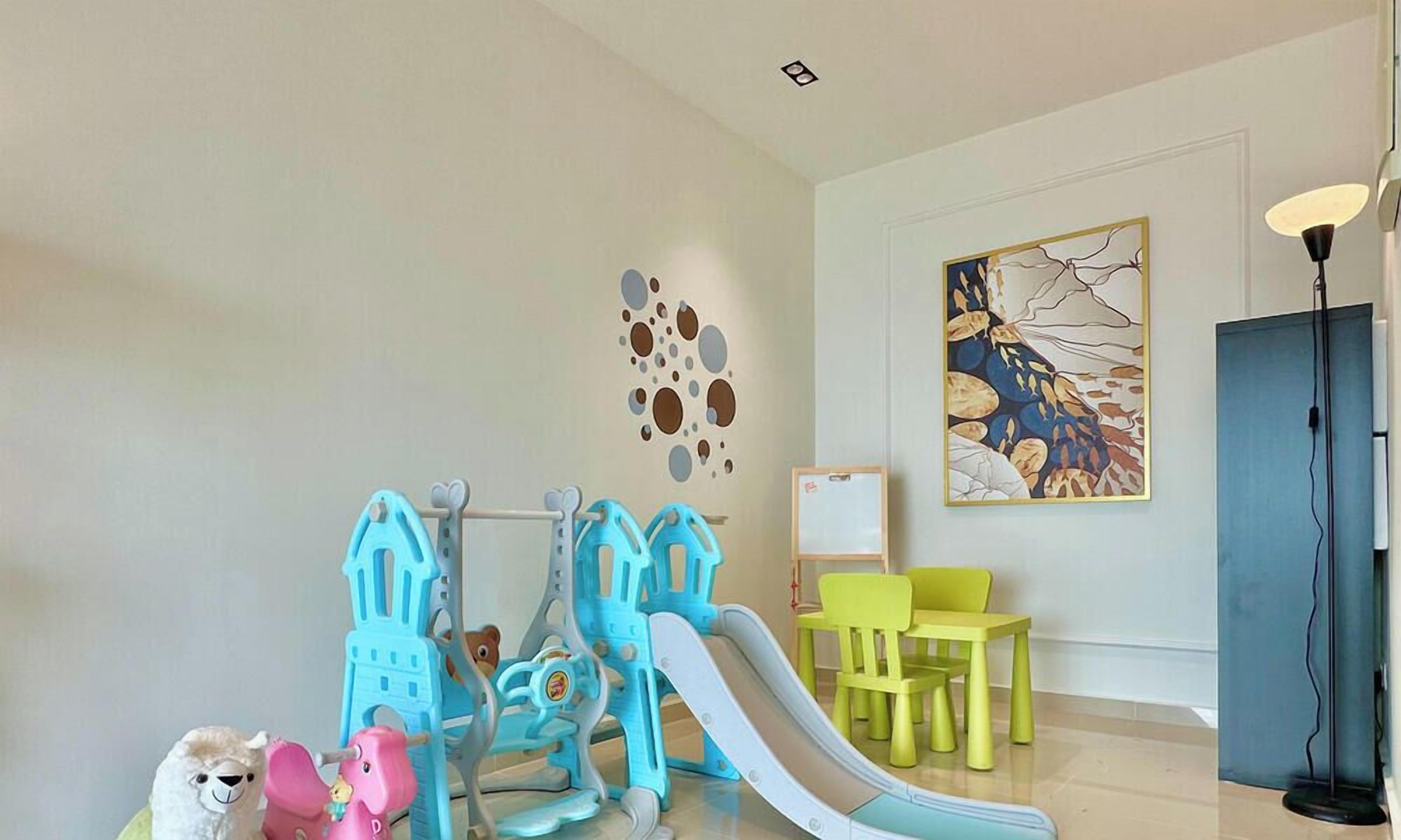 Un área de juegos infantiles con un tobogán, una estructura para escalar y dos sillas pequeñas.