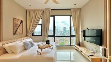 A modern hotel room with a large bed, a flat-screen TV, a desk, and a view of the cityscape.
