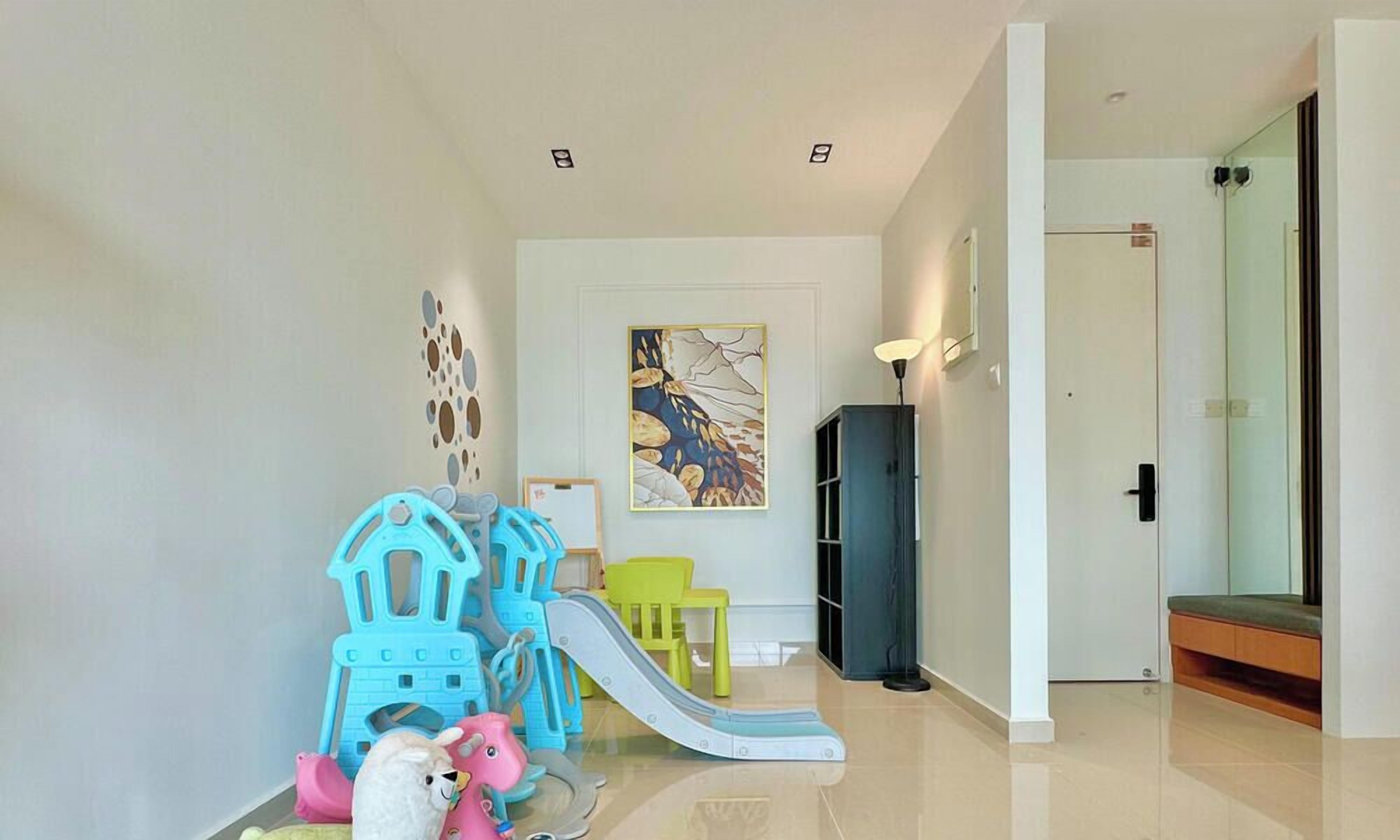 A children's play area with a slide and climbing structures, a refrigerator, and a door leading to a bathroom.