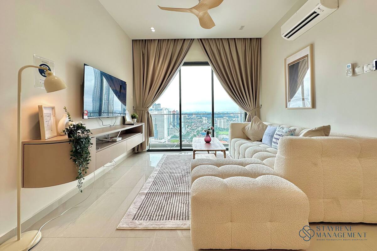 Un salon moderne doté d’une grande fenêtre, d’un ventilateur de plafond et d’un téléviseur à écran plat.