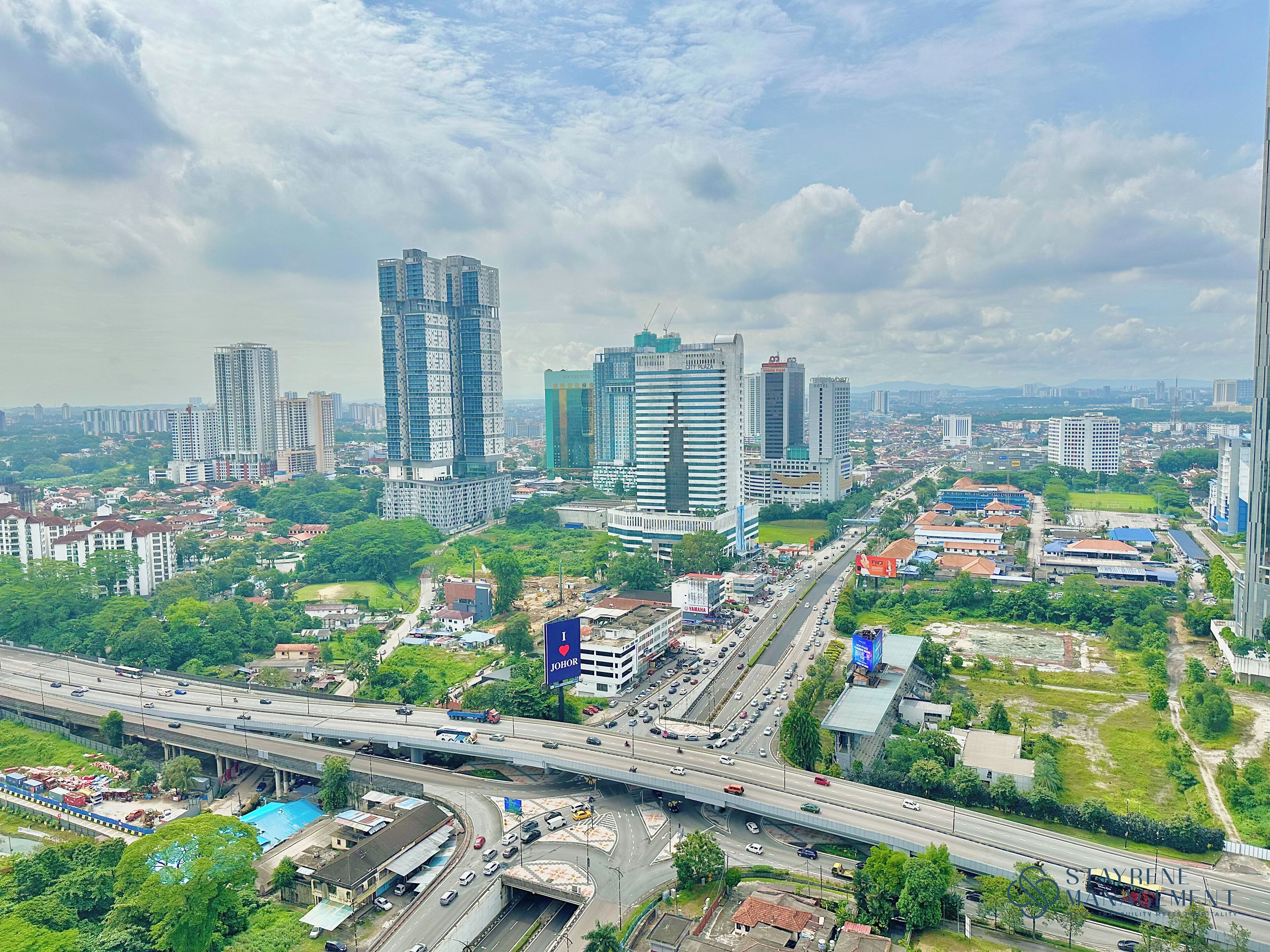 Un paysage urbain avec de hauts immeubles, une autoroute et des espaces verts.
