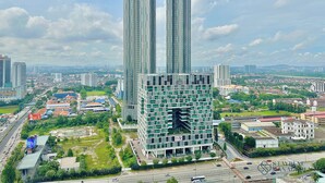 A modern high-rise building with a unique architectural design, surrounded by a mix of commercial and residential buildings.