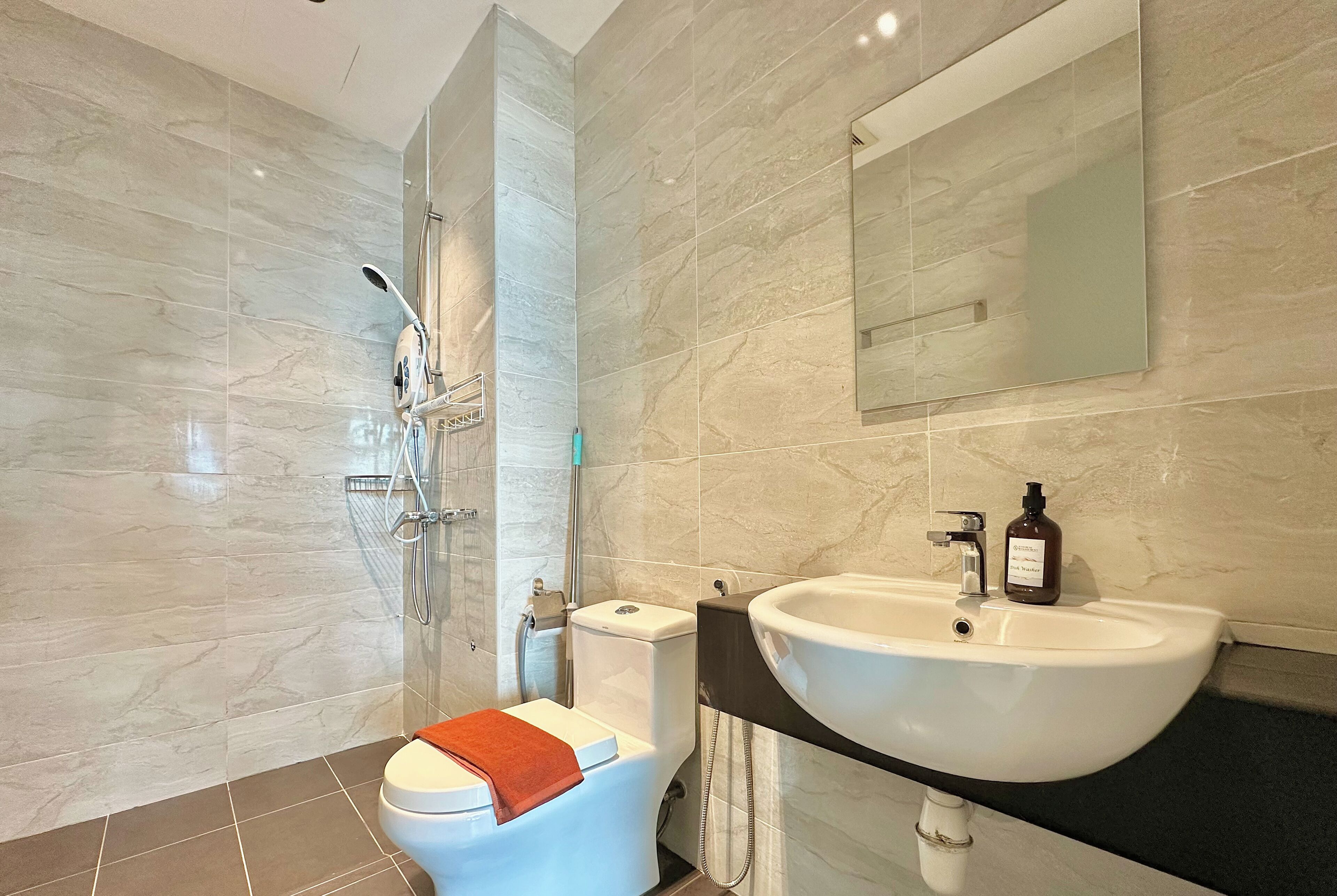 A modern bathroom with a toilet, shower, and sink.