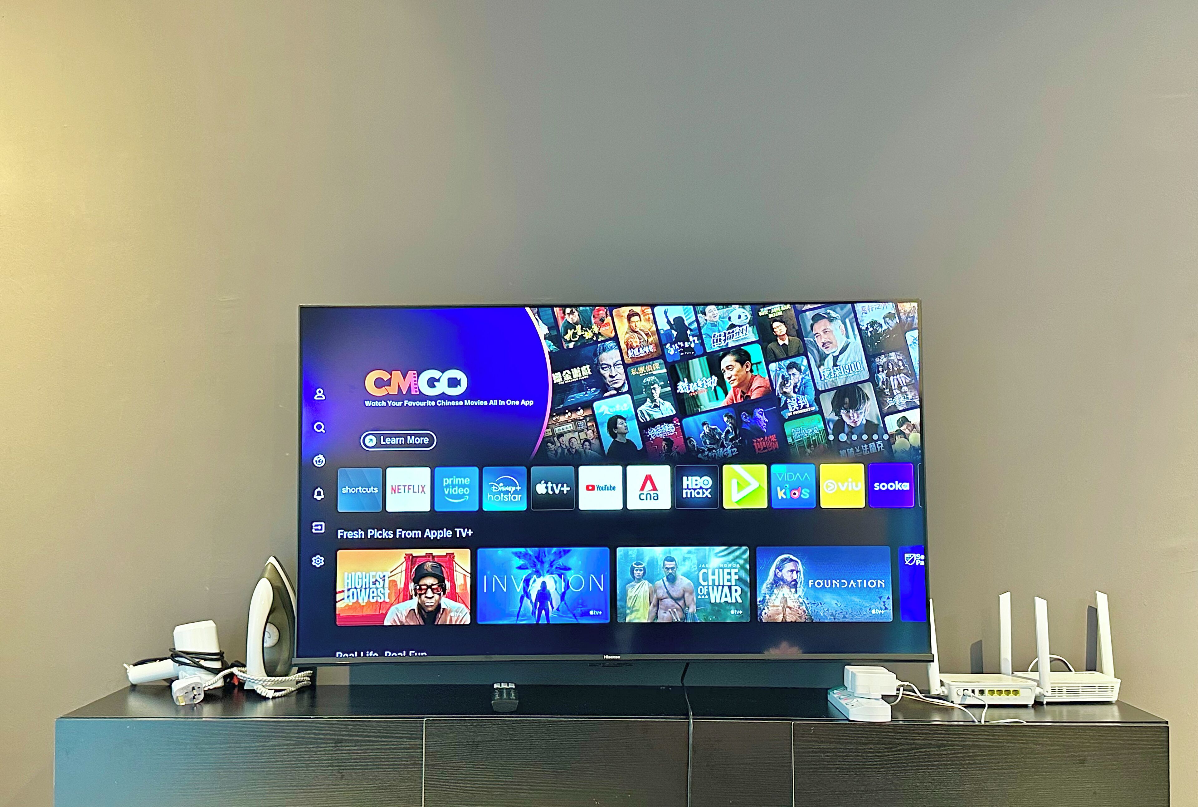 A television displaying a streaming service interface with multiple app icons and a selection of shows.