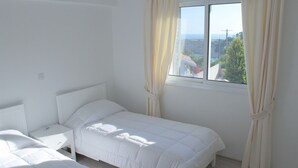 A bedroom with a single bed, a nightstand, and a window with curtains. - Seaview 4 Bedroom villa with pool (Paphos)