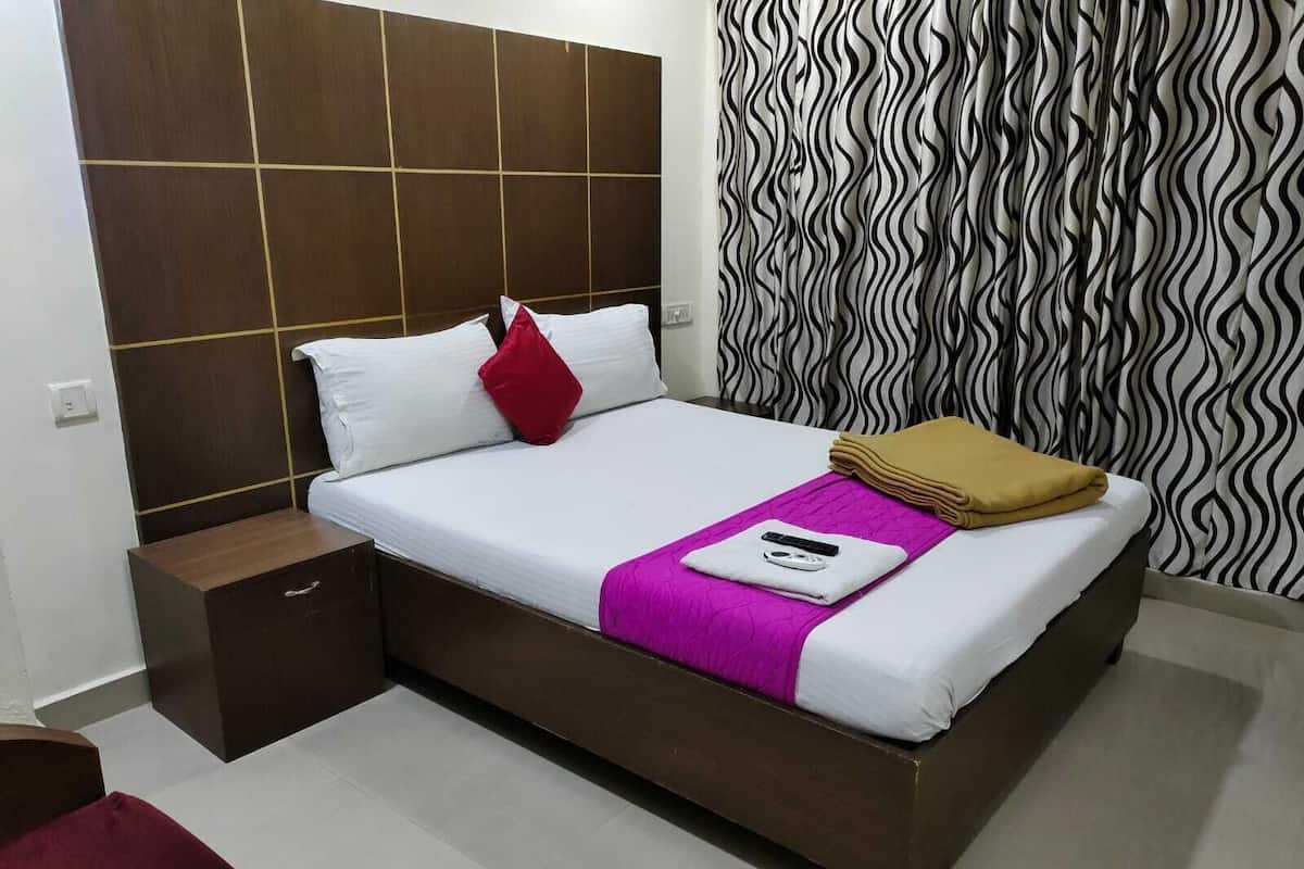 A neatly made bed with white and red pillows, a purple blanket, and a folded towel.