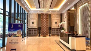 Un hall de hotel con una recepción, una araña y un ventanal grande.