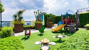 Un parque infantil en la azotea con tobogán, estructuras para escalar y columpios.