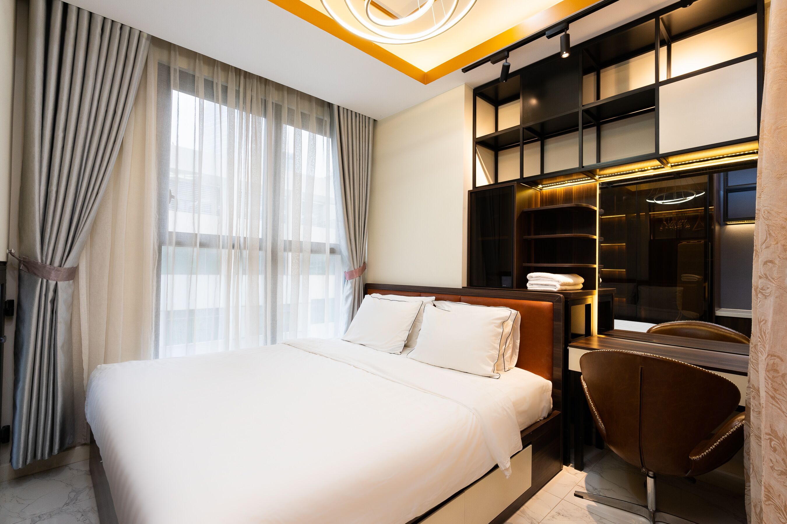 Ein modernes Hotelzimmer mit einem großen Bett, einem Schreibtisch mit Stuhl und einem Einbauschrank.